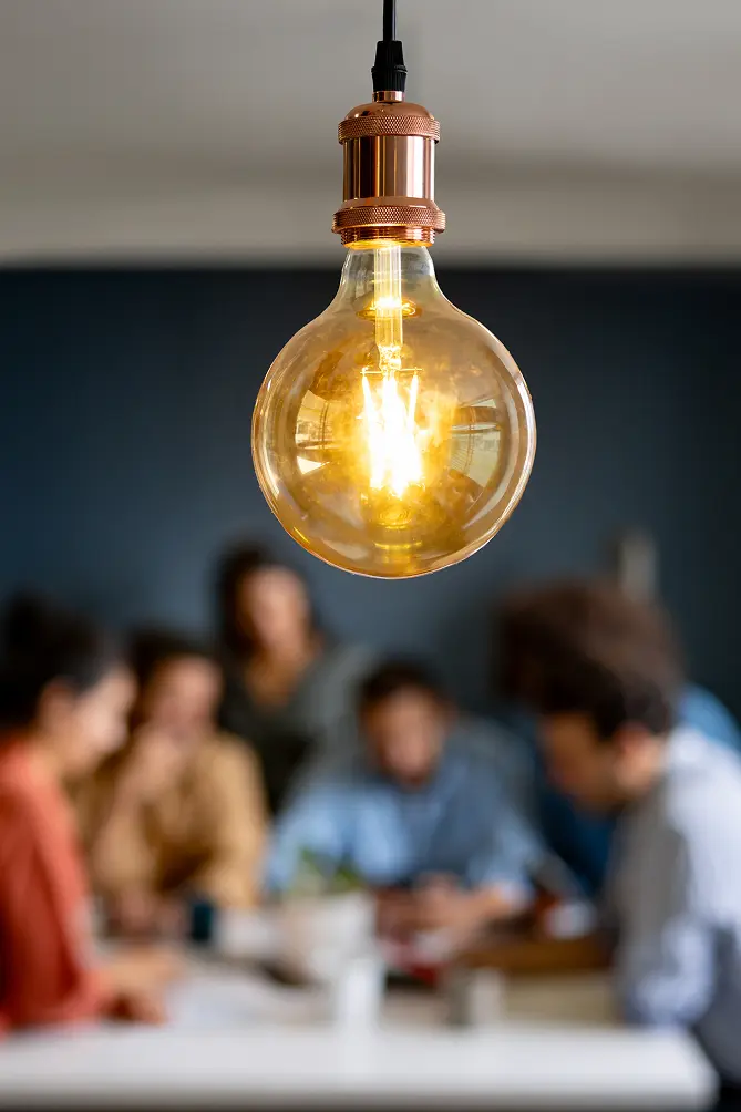 Light bulb with team of workers in the background